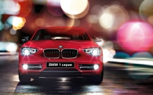 Красный BMW 1 series среди ярких огней ночного города после дождя